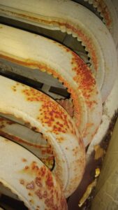 Close-up of rust spots on large, curved metallic pipes in need of maintenance, echoing the search for AC repair near me.